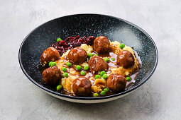 Meatballs in sauce with mashed potatoes, peas and cranberries