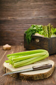 Celery with knife on wooden cutting board