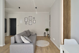 Living room with grey sofa, wooden floor and minimalist art