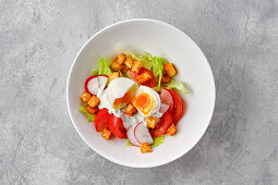 Salad with tomatoes, radishes, croutons and poached egg