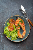 Grilled salmon steak with lemon slices and green salad