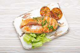 Grilled salmon steak with lemon slices and green salad