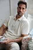 Man in cream polo shirt enjoys espresso