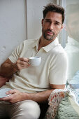 Man in cream polo shirt enjoys espresso