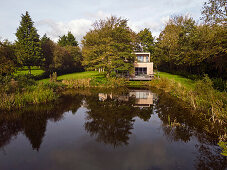 Modern family home with timber cladding and aluminium windows by a pond in Lincolnshire, UK