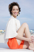 Brunette woman in cream-coloured blouse and orange-coloured shorts