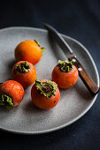 Fresh and ripe persimmons on a grey plate