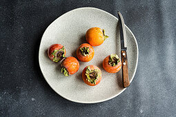 Fresh and ripe persimmons on a grey plate