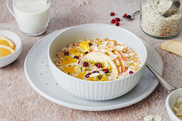 Porridge with apple slices, orange, pomegranate seeds and almonds