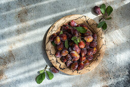 Fresh ripe plums in a wooden bowl