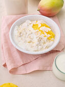 Overnight-Oats mit frisch geschnittenen Mangoscheiben und Kokosflocken