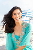 Young woman in turquoise embroidered tunic on the beach