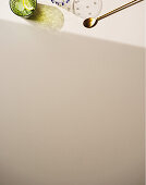 Drink im Glas und goldener Löffel auf hellem Untergrund