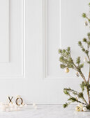 Zweig mit Weihnachtkugeln vor weißem Holzkassetten-Hintergrund