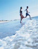 Couple running into water, Sylt, North Sea, Germany