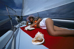 Frau liest ein Buch, Segelschiff Pebbles, Puerto de Mogán, Gran Canaria, Kanarische Inseln, Spanien