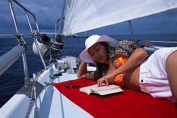 Frau liest ein Buch, Segelschiff Pebbles, Puerto de Mogán, Gran Canaria, Kanarische Inseln, Spanien