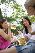 Three girls with beer steins in beer garden, Munich, Bavaria