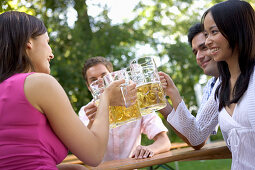 Vier Freunde im Biergarten beim Anstoßen, Starnberger See, Bayern, Deutschland