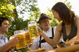 Three people toasting each other with beer steins, Munich, Bavaria