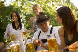 Cheerful people with beer steins in beer garden, Munich, Bavaria
