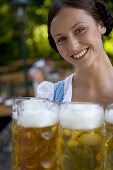 Young woman, waitress carrying beer glasses, beer steins, Lake Starnberg, Bavaria, Germany