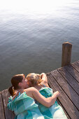 Two girls lying on jetty, Starnberger See, Bavaria, Germany