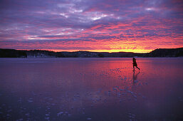 Woman skating on ice, lake in Vastergotland, Sweden