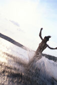 Woman running into the water of a lake