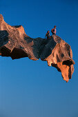 Two hikers on a rock ledge at Capo d´Orso, a bear shaped rock, Sardinia, Italy