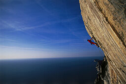 Male free climber scaling rock face, No Siesta 8b, Muzzerone, Portovenere, Cinque Terre, Liguria, Italy