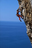 Female free climber scaling rock face, Muzzerone, Portovenere, Cinque Terre, Liguria, Italy