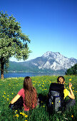 Girls having a rest in a field of flowers, Traun Lake, Traunstein Mountains, Salzkammergut, Austria
