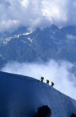 Three alpinists ascending Aiguille du Midi, Chamonix in the background, Alps, France