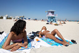 Two young women lying in the sun, beach life, South Beach, Miami, Florida, USA