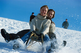 Young couple sledging down a slope, Winter sport