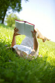 Young Woman reading book on lawn