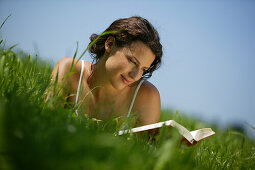 Young Woman reading book on lawn