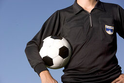 Fußballschiedsrichter hält Spielball im Arm