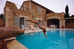 Frau springt in Pool vor einem Landhaus, Côte d'Azur, Frankreich, Europa