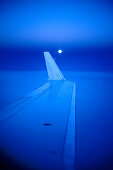 Blick auf Tragfläche eines Flugzeugs bei Mondaufgang