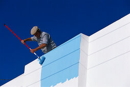 Local man painting his house blue, Thira, Santorini Cyclades, Greece