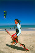 Young man on beach with kiteboarding gear, ready for start