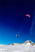 Mann springt beim Snowkiting, Lermoos, Lechtaler Alpen, Tirol, Österreich