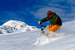 Young man snowscooting downhill, Serfaus, Tyrol, Austria
