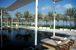 Sun loungers and palm trees at Serai Pool, The Chedi Hotel, Muscat, Oman, Middle East, Asia