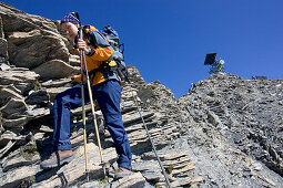 Junge Frau wandert vom Gipfel des Muttlers hinunter, Samnaun, Val Sinestra, Engadin, Graubuenden, Schweiz.