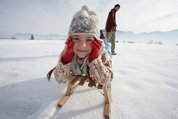 Man pulling daughter in toboggan on snow
