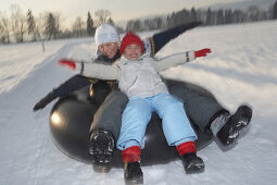 Mädchen und Junge lassen sich mit Autoreifen ziehen Snowtubing