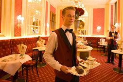 Waiter serving Sachertorte in restaurant Anna Sacher of Hotel Sacher, Vienna, Austria